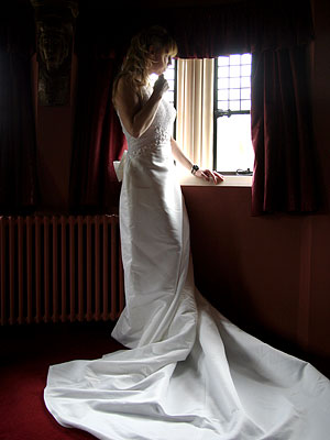 the bride looks out of the window in coombe abbey
